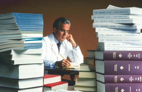 CHEMIST LOOKS UP INFORMATION THROUGH PILE OF PAPERS