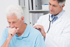 Doctor examining coughing senior patient