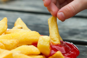 child dipping a chip into tomato sauce