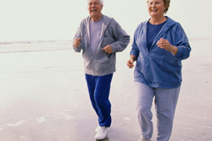 portrait of senior couple jogging on the beach