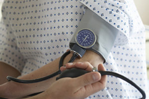 "Male doctor checking woman's blood pressure, mid section"