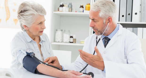 Doctor taking the blood pressure of his retired patient